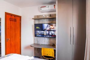 a bedroom with a tv and a yellow chair at Apartamento sofisticado, confortável e bem equipado - Loft Felau in Cuiabá +38 photos