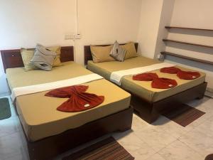 two beds with towels on them in a room at Lilly Rooms in Kandy