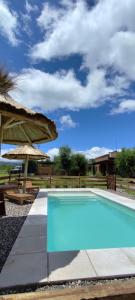 a swimming pool with a umbrella and a table at Alebrijescalamuchita in Villa Ciudad Parque