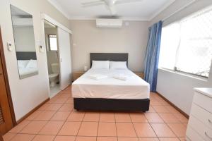 a bedroom with a bed and a bathroom with a window at Royal Palm Villas in Cairns