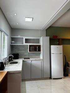 a kitchen with a refrigerator and a microwave at Studio com Garagem, Térreo com Acesso privativo e WIFI, a 5 Minutos do Centro in Poços de Caldas +9 photos