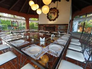 a dining room with a long table with white plates at Posada Los Alcatraces in Atlixco +24 photos