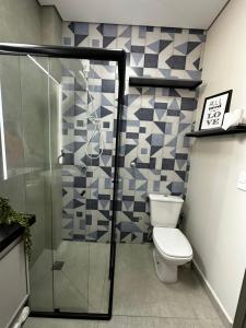 a bathroom with a toilet and a glass shower at Studio com Garagem, Térreo com Acesso privativo e WIFI, a 5 Minutos do Centro in Poços de Caldas