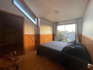 a bedroom with a bed and a large window at Oikos Arriendos in Futrono