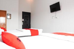 a room with two beds and a tv on the wall at RedDoorz Plus Syariah at Umyas Hotel near Terminal Anjuk Ladang Nganjuk in Nganjuk