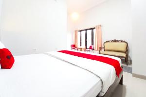 a white bedroom with a bed and a chair at RedDoorz Plus Syariah at Umyas Hotel near Terminal Anjuk Ladang Nganjuk in Nganjuk