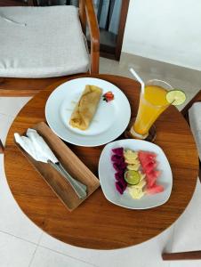 a table with two plates of food and a glass of orange juice at Diara's Cottage in Ubud