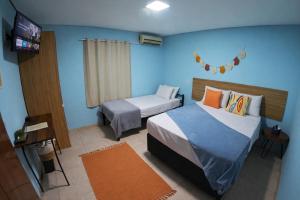 a bedroom with two beds and a television in it at Villa Kanindé Bonito in Bonito