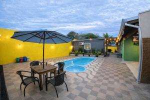 a patio with a table and an umbrella and a pool at Villa Kanindé Bonito in Bonito