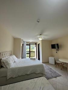 a bedroom with a large bed and a table at Ecopousada Garten Haus in Santa Teresa