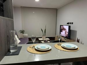 a table with two plates and wine glasses on it at Departamento moderno céntrico con piscina 2 Habitaciones 2 Baños in Chillán +5 photos