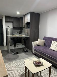 a living room with a purple couch and a kitchen at Departamento moderno céntrico con piscina 2 Habitaciones 2 Baños in Chillán