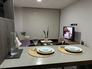 a table with two plates and wine glasses on it at Departamento moderno céntrico con piscina 2 Habitaciones 2 Baños in Chillán