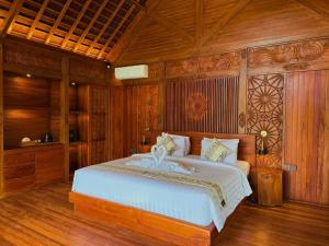 a bedroom with a large bed with wooden walls at Wanataru Sidemen Villas in Sidemen +50 photos
