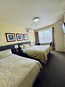 a hotel room with two beds and a window at Knightsbridge Apartments in Melbourne