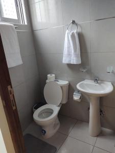a white bathroom with a toilet and a sink at Disfruta Cala-Cala in Cochabamba