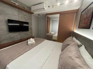 a bedroom with a large bed and a tv at Apart Blend Marista Ar, Cozinha Próx ao Órion in Goiânia