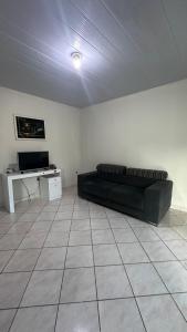 a living room with a black couch and a table at Casa espaçosa e arejada in Garanhuns +1 photo