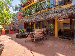 a patio with chairs and a table with a thatched roof at Amare Las Villas in Sayulita