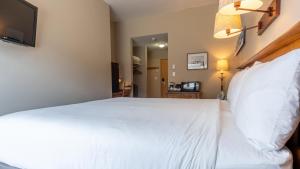 a bedroom with a white bed and a television at Cahilty #108 home in Sun Peaks