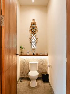 a bathroom with a toilet and a mirror on the wall at Leafy Riverbank in Tabanan