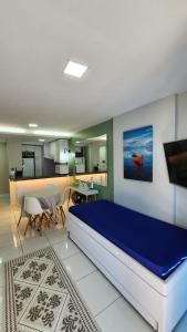 a bedroom with a large blue bed and a kitchen at Studio Costa a Mar in Guarapari