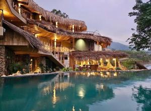 a resort with a swimming pool in front of it at Puluong Qui E Ora in Lũng Tiềm