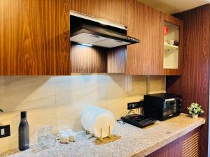 a kitchen with a microwave and a counter with wine glasses at Studio in Dehradun in Dehradun