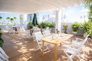 a patio with white chairs and a wooden table at Xavia Hotel in Quy Nhon