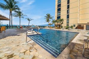 a pool at a resort with palm trees and a building at Mahana 718 in Lahaina
