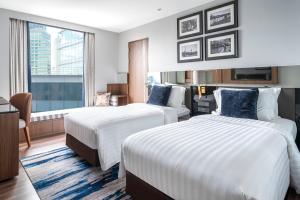 a hotel room with two beds and a window at Montraj Continent Sukhumvit Bangkok in Bangkok