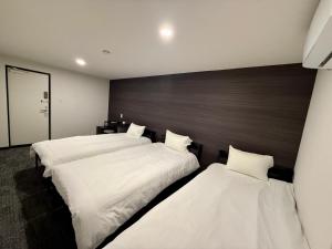 zwei Betten in einem Hotelzimmer mit weißer Bettwäsche in der Unterkunft HOTEL STAY Plus in Imabari