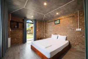 a bedroom with a bed and a brick wall at Newlife Homestay & Restaurant in Dong Hoi