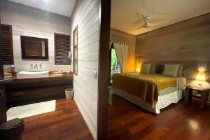 a bedroom with a bed and a bathroom with a sink at Villa Anani in Papetoai