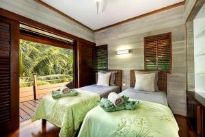 two beds in a room with a balcony at Villa Anani in Papetoai +49 photos