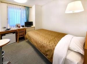 a hotel room with a bed and a desk with a computer at Hotel Trend Funabashi in Funabashi