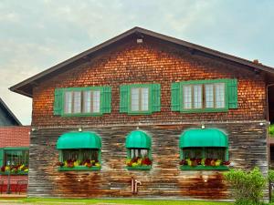 a brick house with green windows and flowers on it at Riverview Lodge in Dryden