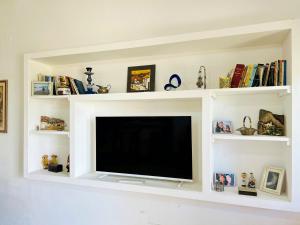 a flat screen tv in a living room with white shelves at LA ESQUINA DE LA FLOR in Campo Quijano