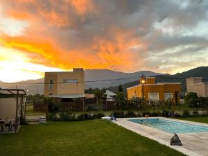 a house with a swimming pool and a sunset at LA ESQUINA DE LA FLOR in Campo Quijano