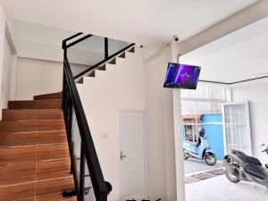 a living room with a staircase and a tv on a wall at G-House-2 in Singkawang