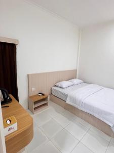 a bedroom with a bed and a wooden table at G-House-2 in Singkawang