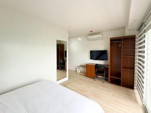a bedroom with a bed and a desk and a television at The Nest Bed and Breakfast - Kalibo in Kalibo +13 photos