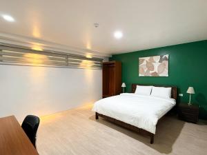 a bedroom with a large bed and a green wall at The Nest Bed and Breakfast - Kalibo in Kalibo