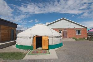 a yurt sitting in a parking lot next to a building at BTMongolia Guest house Tour Operator in Ölgiy
