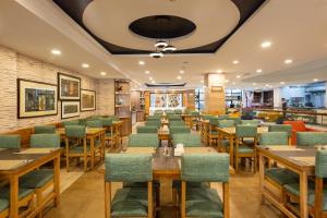 a restaurant with wooden tables and green chairs at Hotel Arts Kathmandu in Kathmandu
