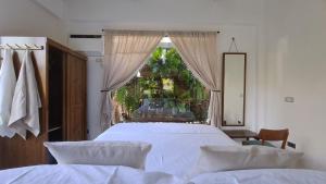 a bedroom with a large bed and a window at Casa Munti Garden Lodge in Daet