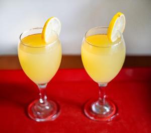 two glasses of orange juice with a lemon slice on a red table at Anu Villa Wadduwa in Wadduwa