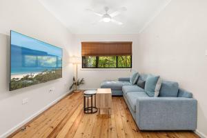 a living room with a blue couch and a table at Husky Days in Huskisson
