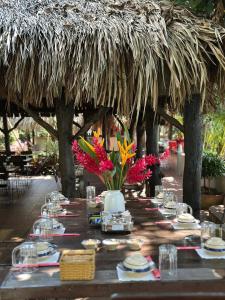 a table with plates and flowers in a thatch umbrella at Mekong Rustic Riverside in Ấp An Nhơn (3)