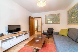 a living room with a couch and a flat screen tv at Casa Mirabella in Sottoguda